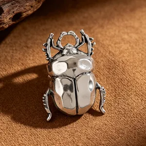 Detailed macro shot of a vintage silver-finish metal beetle ring on a textured surface