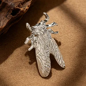 Macro detail view of a silver cicada-shaped metal ring with intricate textures.