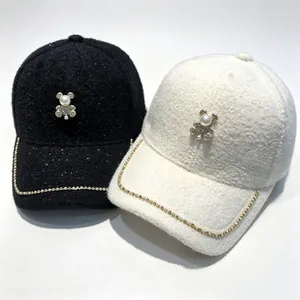 Detailed view of warm plush baseball caps featuring a pearl bear and rhinestone chain accents.