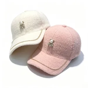 Close-up detail of plush baseball caps featuring pearl bear and rhinestone gold chain trim