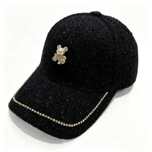 Detail of black tweed baseball cap with rhinestone trim and pearl bear ornament