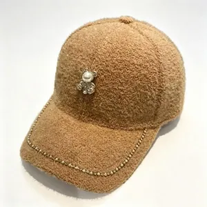Plush brown baseball cap with pearl bear and rhinestone chain detail for winter season.