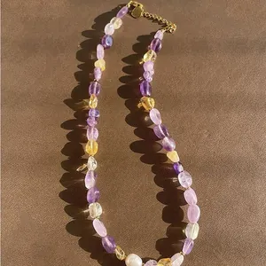 Close-up detail of a colorful natural stone beaded necklace with a white freshwater pearl