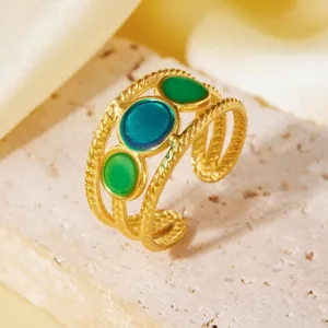 Dettaglio dell'anello intrecciato in acciaio al titanio dorato con tre pietre.