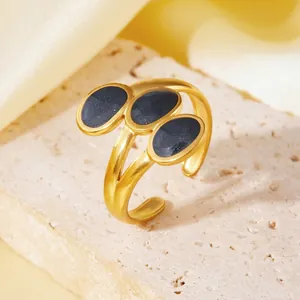 Dettaglio dell'anello in titanio dorato con tre pietre ovali scure scintillanti.