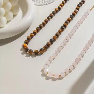 Close-up detail of faceted tiger eye and rose quartz beaded necklaces with gold accents