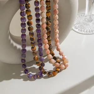Close-up of faceted natural stone necklaces with gold spacers on white vase