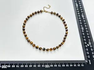 Detail view of a faceted tiger eye necklace with a ruler showing precise measurements.