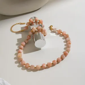 Detail of a natural peach stone necklace with faceted beads and gold stainless steel chain