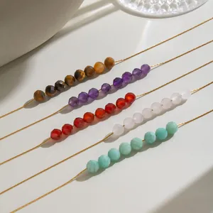 Gros plan de colliers en perles de pierre naturelle colorées sur fines chaînes en or