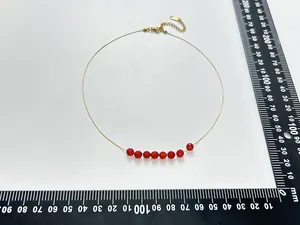 Vue détaillée d'un collier en acier inoxydable doré avec perles rouges et règle de mesure