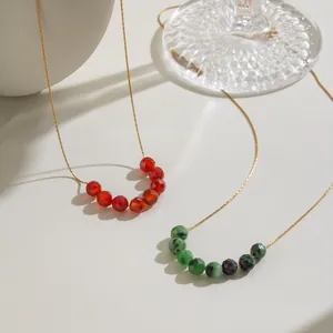 Détail de perles en pierre naturelle colorée sur une fine chaîne en acier doré.