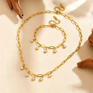 Gold plated stainless steel necklace and bracelet set with clear zircon charms on sand