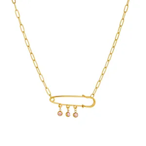 Close-up detail of gold titanium steel safety pin necklace accented with pink crystals
