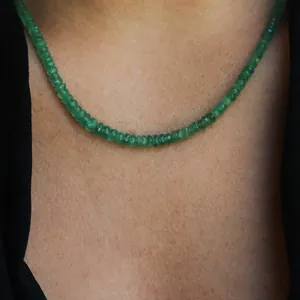 Close-up detail of a handmade green natural stone beaded necklace on a model.