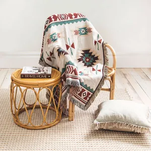 Couverture bohème tissée avec motifs géométriques drapée sur une chaise en rotin élégante