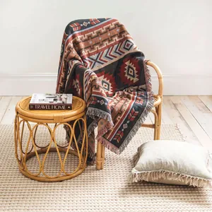 Couverture bohème tissée avec des motifs géométriques colorés drapée sur une chaise en rotin