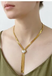 Vue détaillée d'un collier en acier titane doré avec perle en cœur et glands.