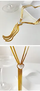 Gros plan d'un collier doré avec pendentif cœur en perle et chaîne à pompons
