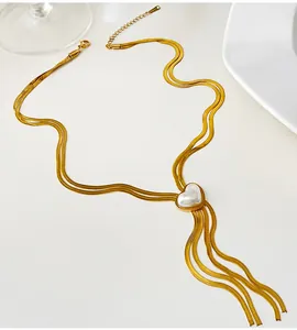 Détail du collier chaîne serpent dorée avec pendentif perle cœur et pompon.