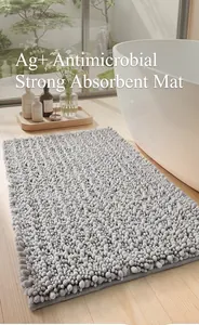 Close-up of grey chenille bath mat showing shaggy absorbent texture by a bathtub