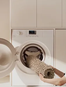 Chenille bath mat being placed in a washing machine to show machine washability