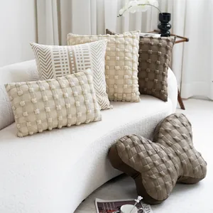 Close-up detail of cream and brown textured decorative pillows on a white boucle sofa