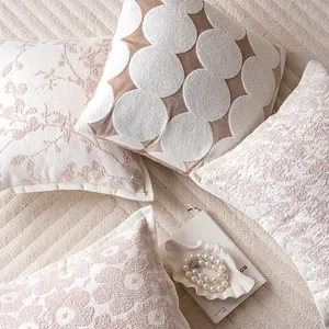 Close-up of cream and pink textured pillow covers with modern patterns in a cozy scene.