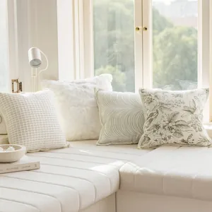 Cozy cream-toned throw pillow covers with diverse textures in a sunlit window seat setting.