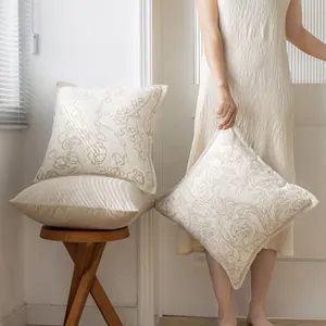 Dettaglio delle federe per cuscini jacquard color crema in una stanza