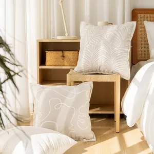 Detail of cream Nordic style throw pillow covers with leaf and abstract line patterns