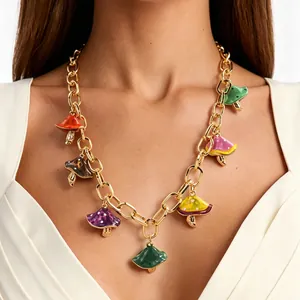 Dettaglio di ciondoli a fungo in smalto vivace su una collana a catena d'oro alla moda