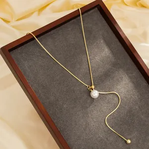 Detailweergave van een goudkleurige roestvrijstalen slangenketting met witte parelhanger