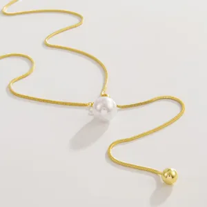 Close-up van gouden slangenketting met grote parelhanger en verstelbare gouden kraal