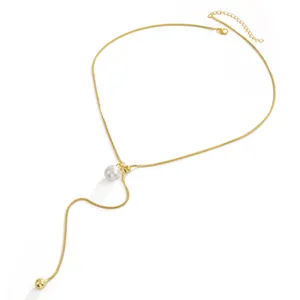 Detail van een goudkleurige roestvrijstalen lariat ketting met een parelhanger