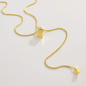 Gedetailleerd zicht op gouden roestvrijstalen slangenketting met kubusvormige hanger