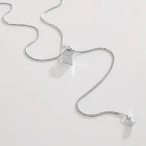 Detail van zilveren roestvrijstalen slangenketting met geometrische kubus hanger