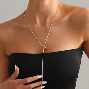 Detail van een minimalistische gouden roestvrijstalen lange ketting met hart hanger op model