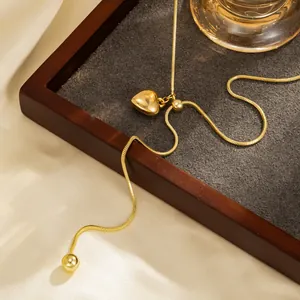Gedetailleerde close-up van een gouden hartvormige hangerketting op een houten dienblad.