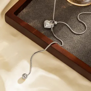 Gedetailleerd beeld van een zilveren hartjesketting met gladde slangenketting