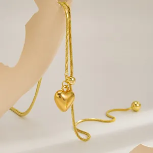 Detailopname van een gouden hartjes hanger aan een verstelbare roestvrijstalen ketting