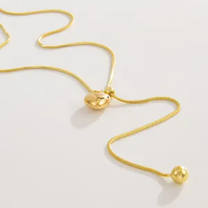 Detail van gouden roestvrijstalen ketting met verstelbare hart hanger en ronde metalen bal