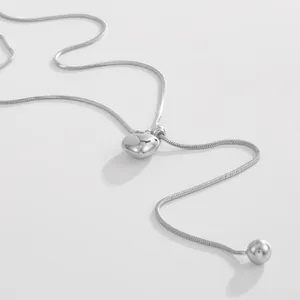 Detailopname van zilveren roestvrijstalen slangenketting met hartvormige hanger en kraal