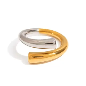 Vue rapprochée d'une bague enveloppante bicolore minimaliste en acier doré et argenté.