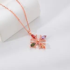 Dettaglio di una collana in oro rosa con ciondolo a croce in zircone multicolore