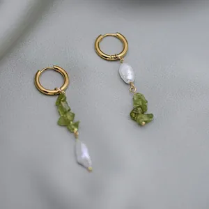 Vue détaillée de boucles d'oreilles en titane doré 18k avec pierre verte et perle