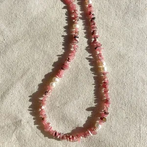 Détail macro d'un collier de pierres roses irrégulières et de perles d'eau douce blanches.