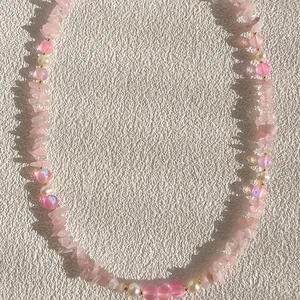 Gros plan d'un collier avec des perles de pierre rose irrégulières et des perles d'eau douce.