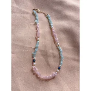 Détail d'un collier en pierres irrégulières et perles d'eau douce sur tissu rose