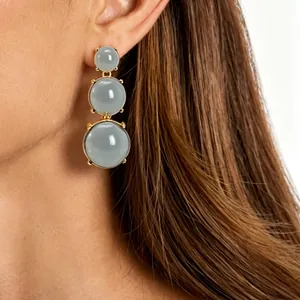 Close-up view of elegant three-tier grey jelly stone drop earrings worn by a model